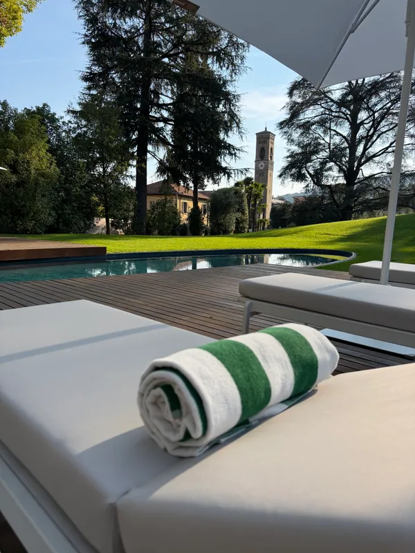 A striped pool towel and sun loungers overlooking a village tower