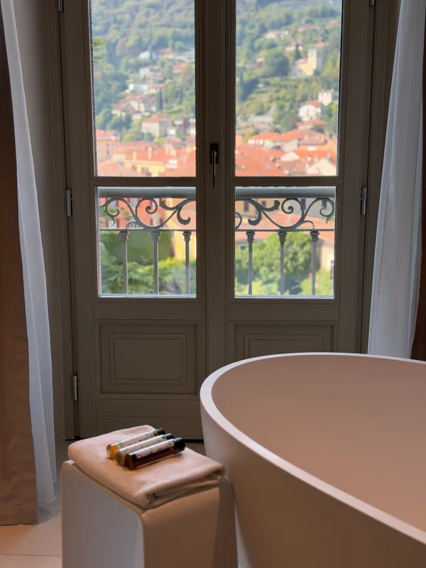 A freestanding bath beside a window overlooking an Italian town