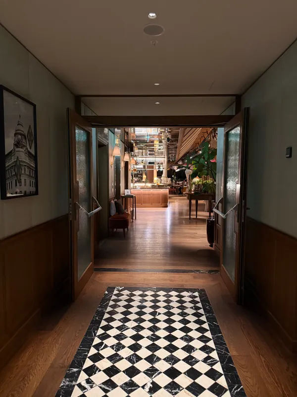 A warm wood corridor leading into a hotel restaurant