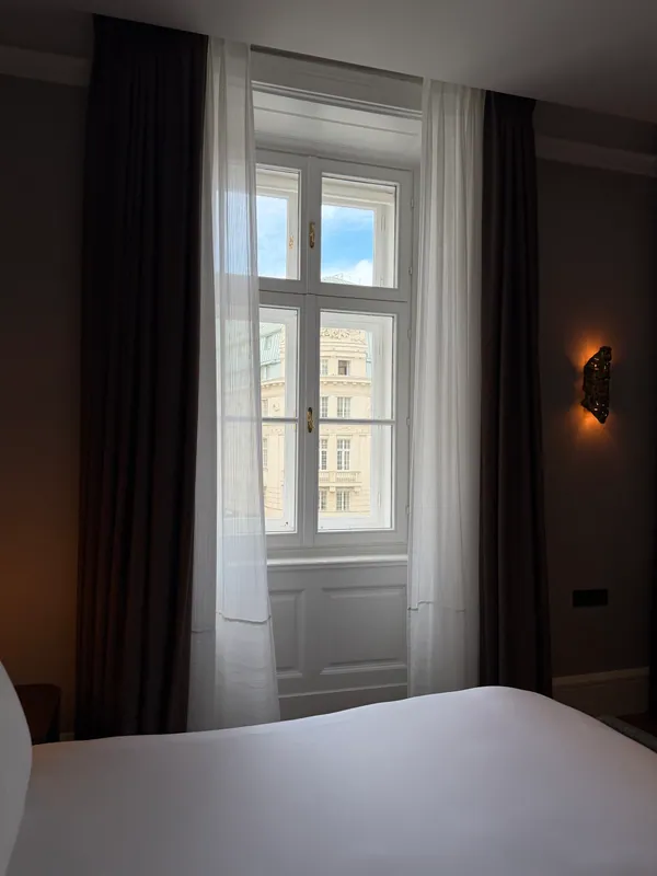 A tall city-facing window framed by curtains in a hotel bedroom